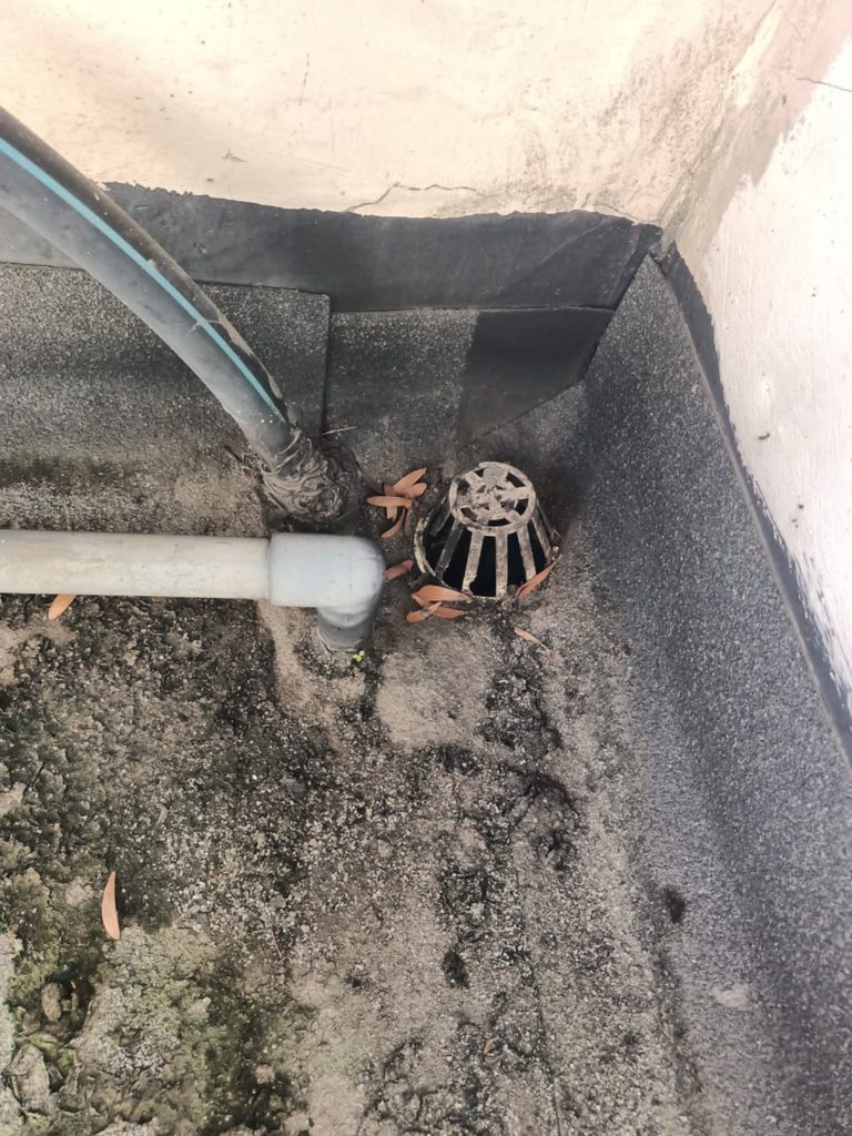 Existing waterproofing membrane around the roof outlet, pipe penetrations and wall upturn before repair at Cascadia.